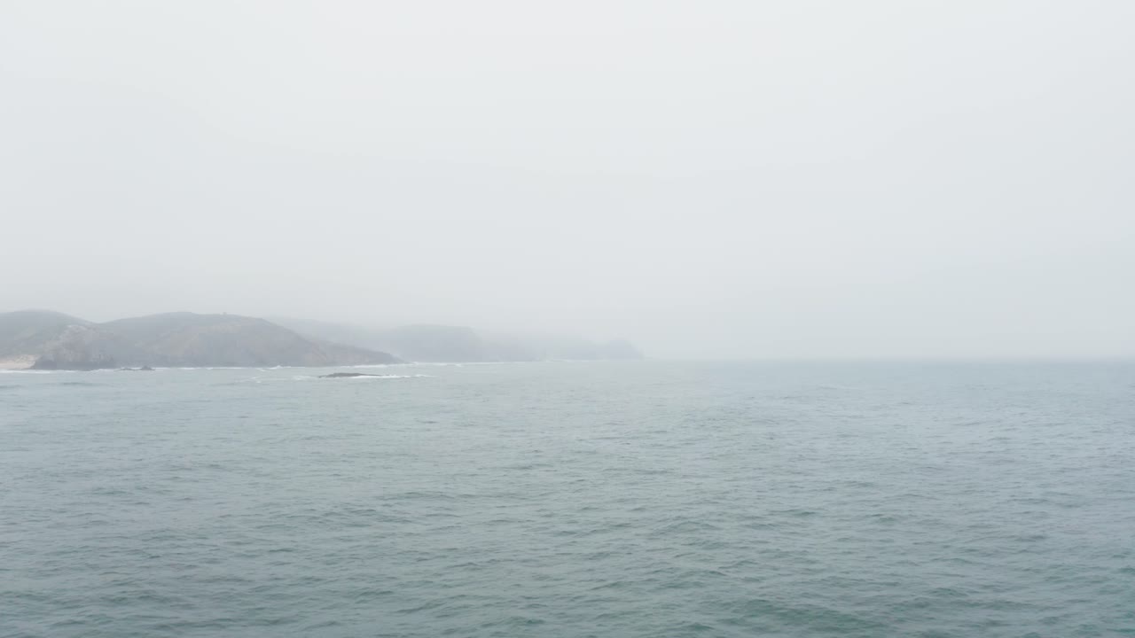 Seascape With Mountains Silhouettes Under Overcast Sky In Portugal. - Aerial Shot