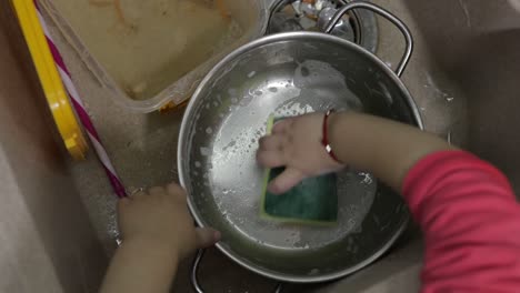 niño lavando platos en la cocina. primer plano de las manos de las niñas