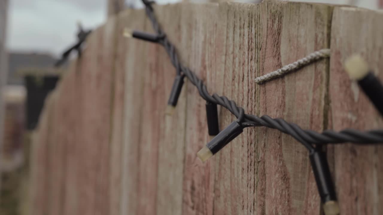 Decorative lights hanging on a wooden garden fence