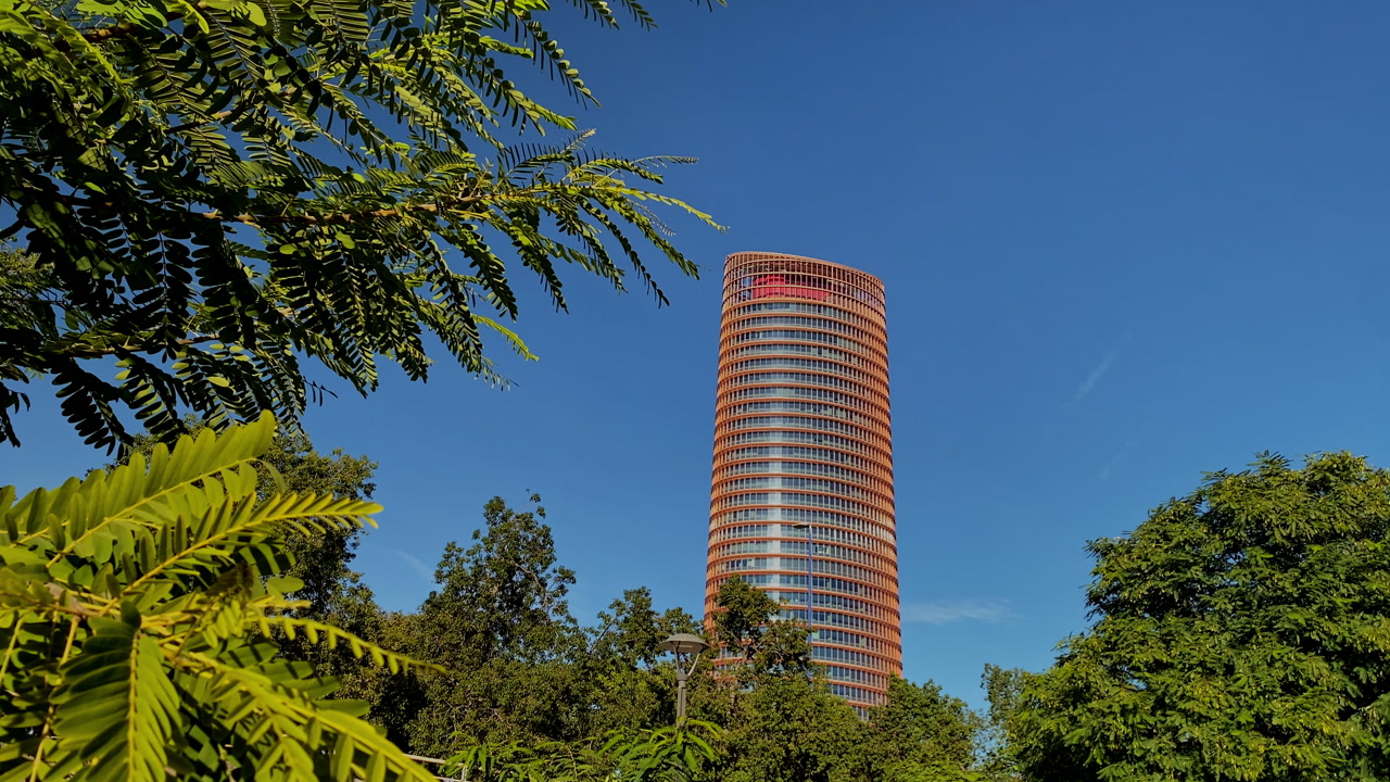 the Crowded outdoor terrace in Triana with Torre Sevilla rising behind under a bright blue sky and vibrant urban energy