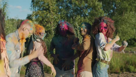 excited men and women covered with powder paint dancing having fun at holi party