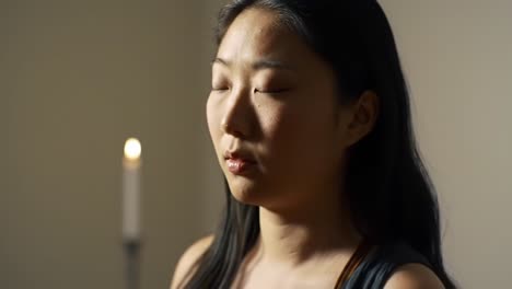 a serene moment of contemplation - a close-up capture of a young woman with closed eyes, illuminated by the soft glow of a candlelight, emphasizing tranquility and inner peace