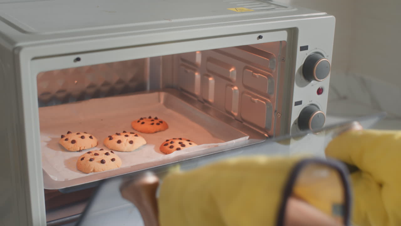 Mani di donna che toglie i biscotti dal forno