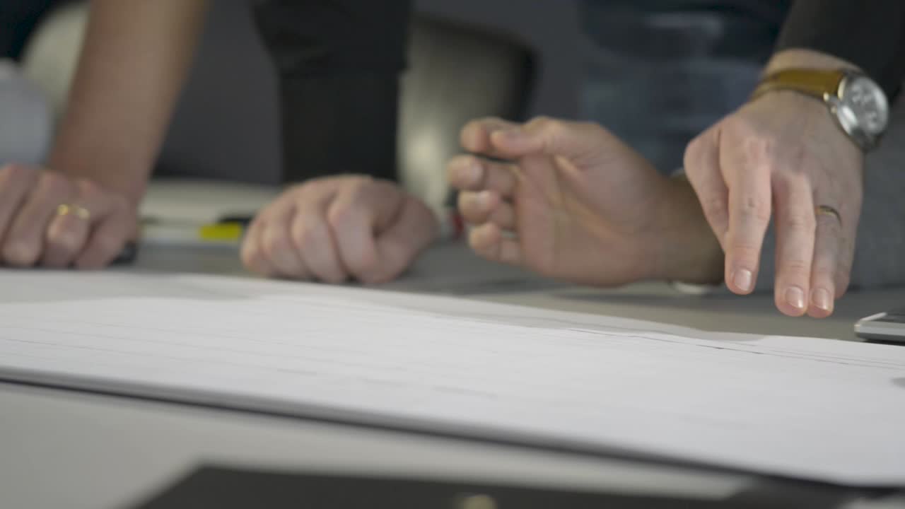 건축 계획을 작업하는 손, 종이와 움직임에 초점을 맞추십시오.