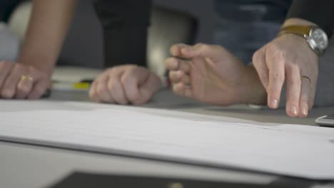 manos trabajando en planes arquitectónicos, centrarse en el papel y el movimiento