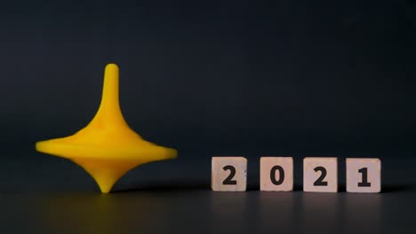 tapa de plástico giratoria de hanukkah vibrante sobre un fondo oscuro junto a cuatro bloques de madera con la fecha 2021 enunciada