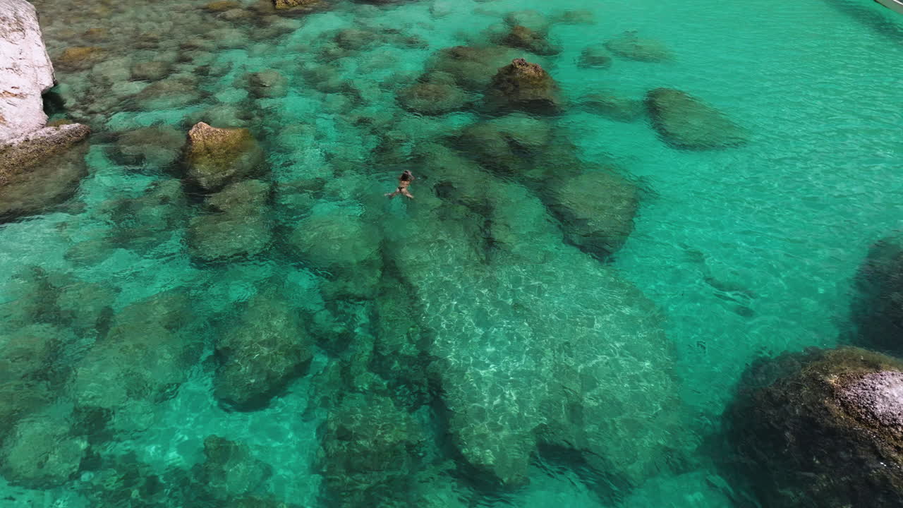 Woman In Bikini Swimming In The Clear, Turquoise Water Of Shoab Coast In Socotra Island, Yemen. - aerial shot