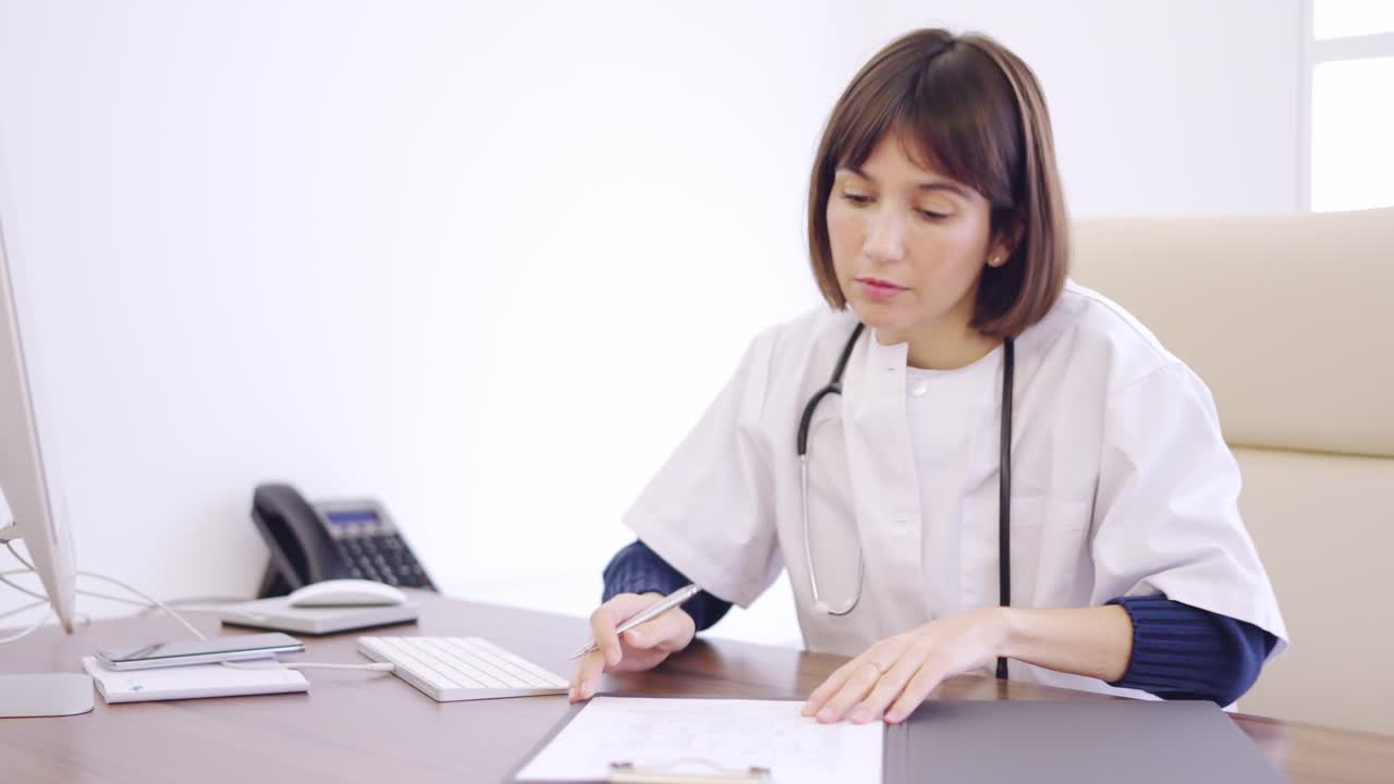Female doctor filling a medical report sitting on a clinic