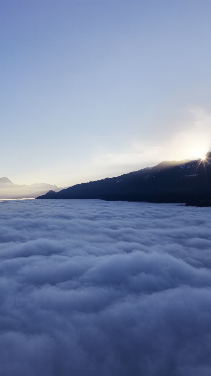 Montagne Churfirsten, Svizzera, con la luce soffusa dell'alba sopra un denso mare di nuvole mentre un drone verticale si alza in una calma atmosfera alpina