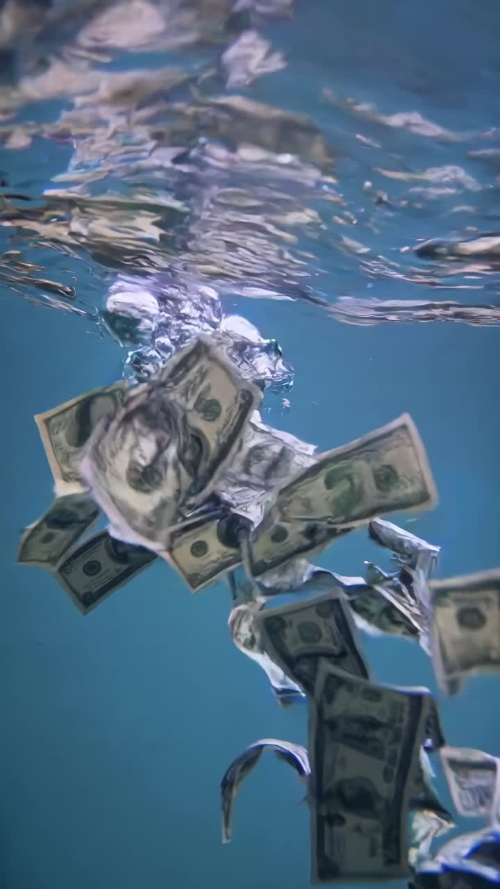 Video subacqueo girato dal basso, che cattura banconote da un dollaro che galleggiano e turbinano, creando un effetto dinamico