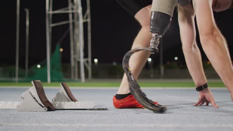 sección baja de atleta masculino caucásico discapacitado con cuchilla de correr preparándose para comenzar una carrera