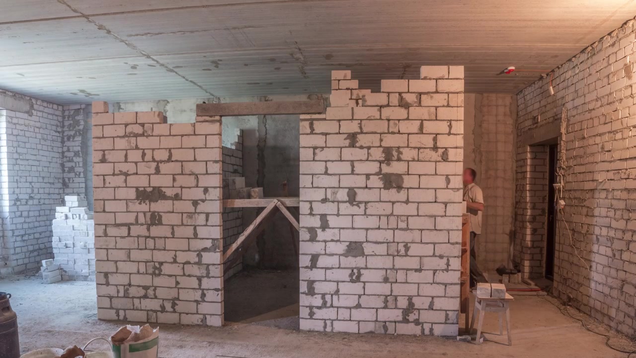Builders laying brick walls inside appartment with professional tools timelapse. Workmen at work, bricklayers building wall, contractor and worker. Building materials around