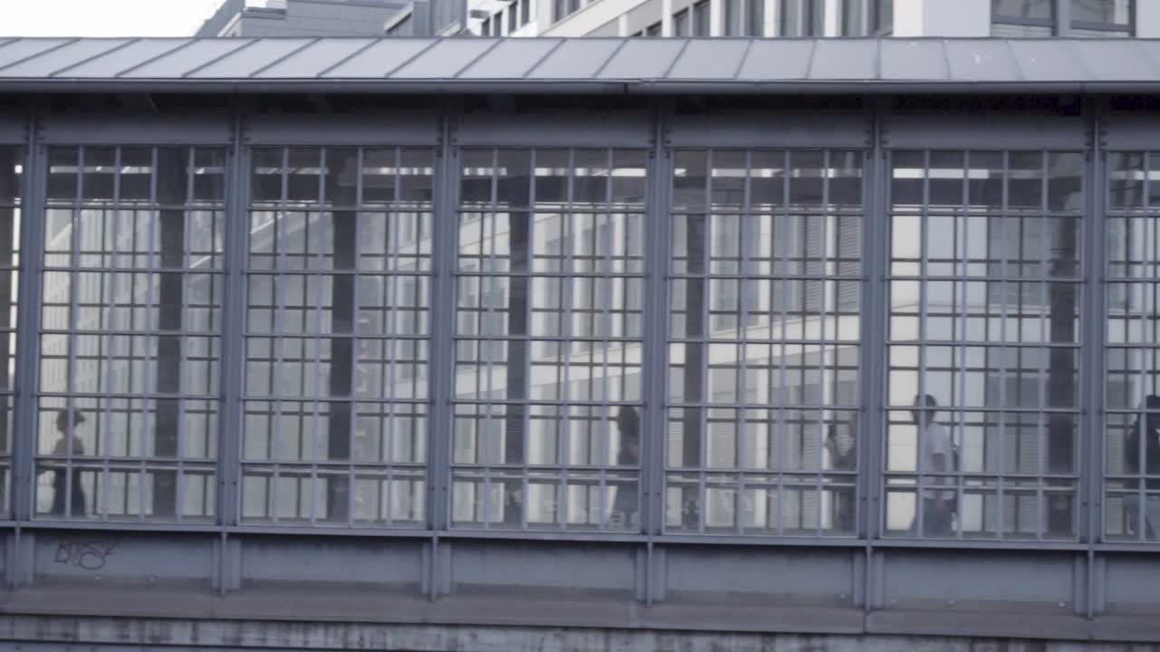 cámara lenta: la gente filmada a través de las ventanas camina por el puente del túnel