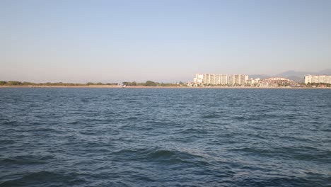 Océano-Desde-Un-Barco-En-Puerto-Vallarta,-México-Con-La-Ciudad-Al-Fondo