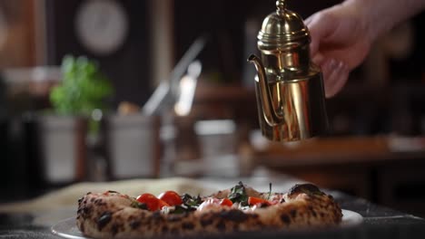 chef drizzling olive oil on pizza