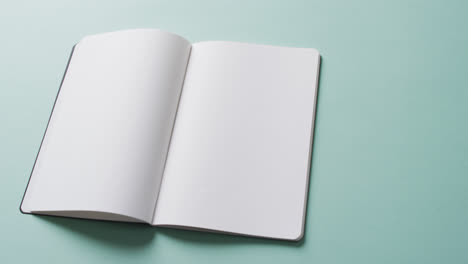 close up of open blank book with copy space on green background in slow motion