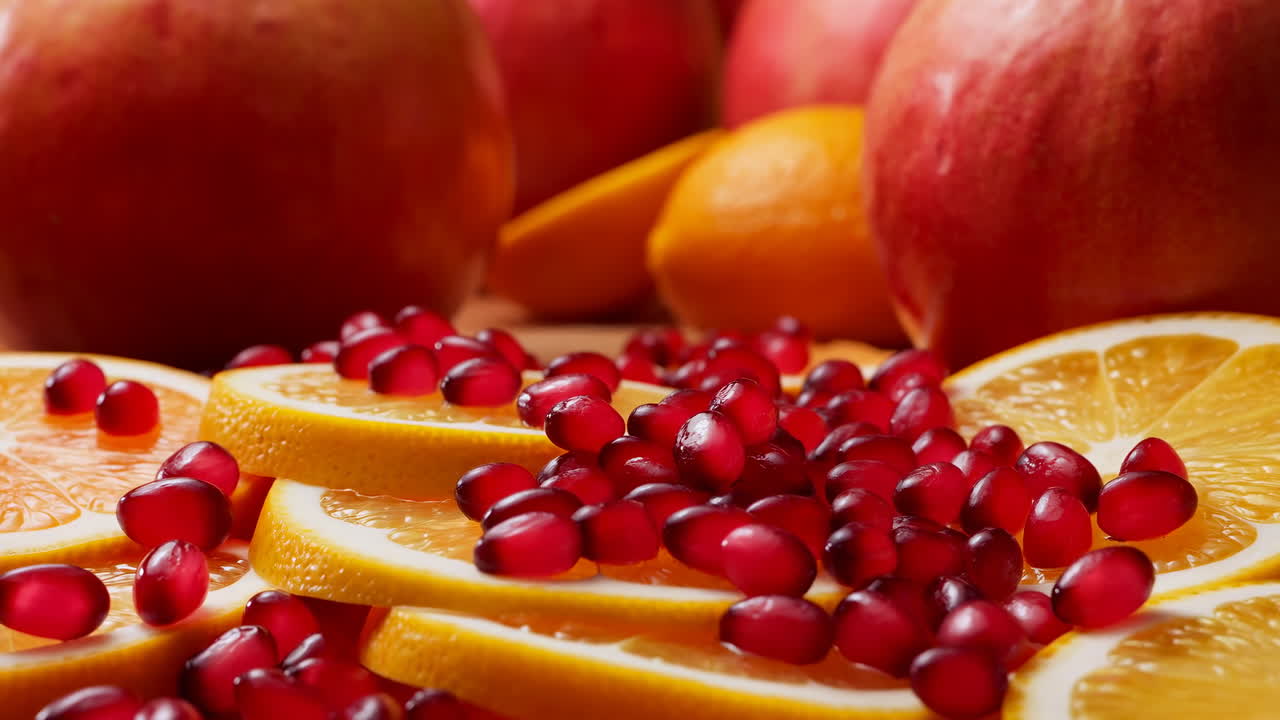 Nærbillede af appelsinskiver, granatæblekerner, æble. Madstylist arrangerer levende citrusfad med blank overflade i studie