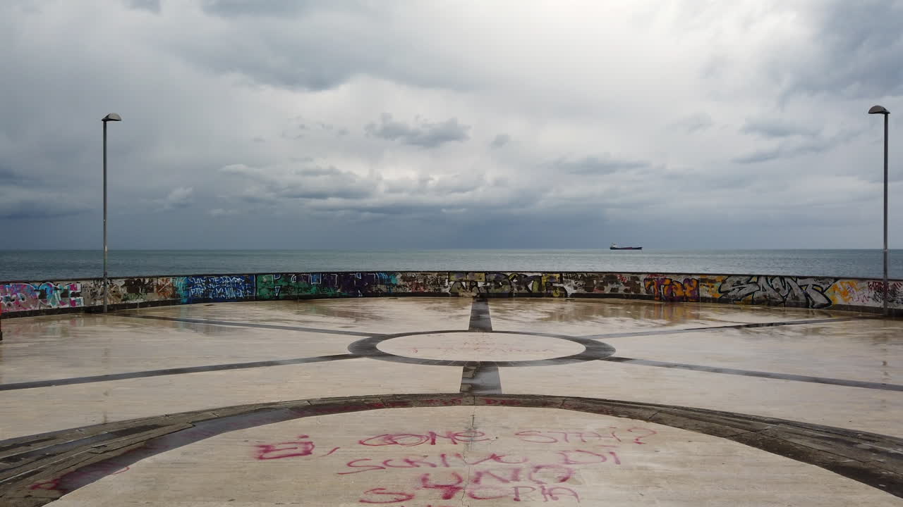 Graffiti-Covered Seascape: A View from a Circular Stone Plaza