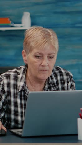 vertical video: old middle aged businesswoman working at laptop from home