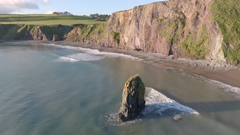 drone circling sea stack at hidden cove copper coast waterford ireland at golden hour