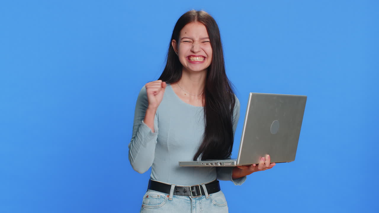 mujer joven muy feliz trabajando en una computadora portátil celebra el éxito gana dinero en la lotería consigue buenas noticias en línea