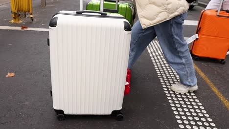 people navigating crosswalk with large suitcases