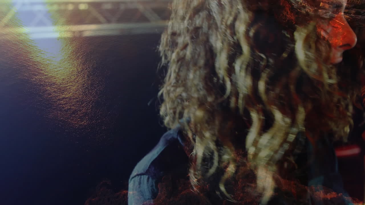 Performer holding microphone facing ocean and cliffside village, displaying animated music bars