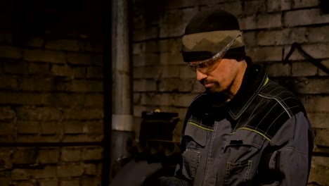 portrait of blacksmith sawing metal with hand circular saw