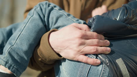 a close-up of adult carrying a small child who is sleeping, with the adult's hand securely holding the child, with a blurred background