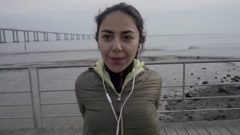 smiling young hindu woman with earphones warming up before workout