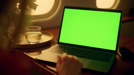 mujer mira la pantalla verde de la computadora portátil en un vuelo de primera clase. manos touch pad closeup