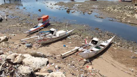 Local-Indonesian-wooden-fishing-boats-and-canoes-moored-along-shoreline-in-Labuan-Bajo-of-Flores-Island,-Indonesia