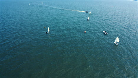 Drohnenaufnahme-Von-Optimisten-Schlauchbooten,-Die-An-Sonnigen-Tagen-Auf-Dem-Meer-Segeln