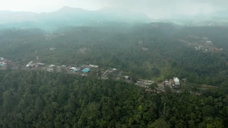 aerial video; drone slowly pans up from city to reveal jungle and mountains in the background