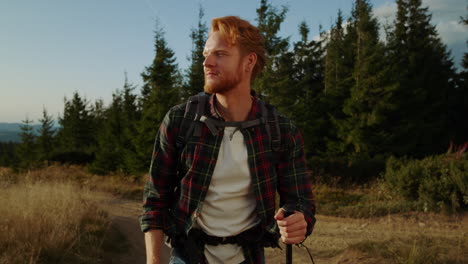 hombre pelirrojo caminando felizmente por el camino de la montaña