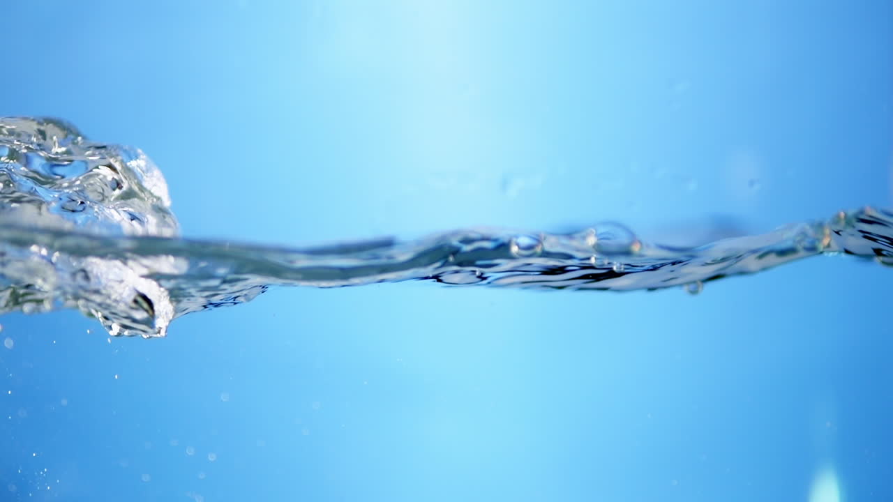 Beautiful slow-motion shot of pristine water surface, highlighting vibrant blue waves that represent clarity and freshness.