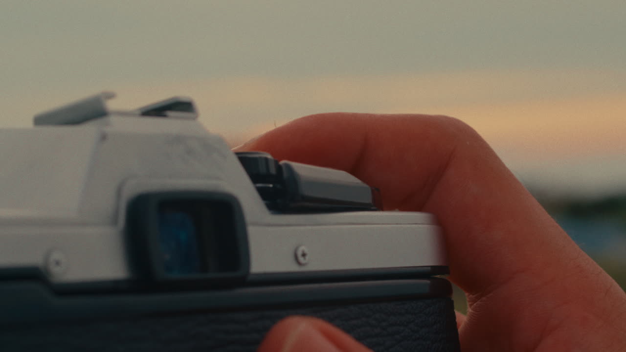 Hand holding a vintage camera at sunset/sunrise
