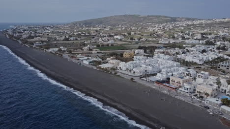 Toma-Aérea-Del-Pueblo-De-Arena-Negra-De-Perissa,-En-La-Isla-Griega-De-Santorini