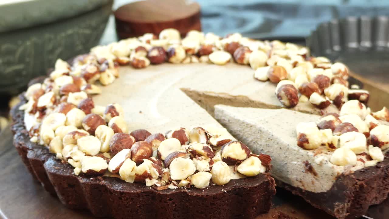 A delicious dessert, Coffee Hazelnut Cream Tart. Made with espresso powder, chocolate crust and loaded with crushed hazelnut. Cutting a piece of chocolate hazelnut espresso pie to put on a plate