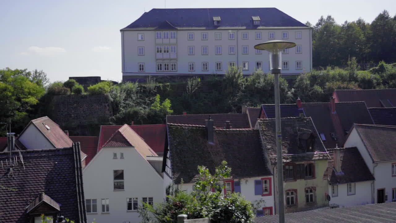 A peaceful slow-motion shot capturing the charming rooftops of Blieskastel, Saarland, Germany. Traditional architecture nestled against lush greenery, creating a serene European townscape.