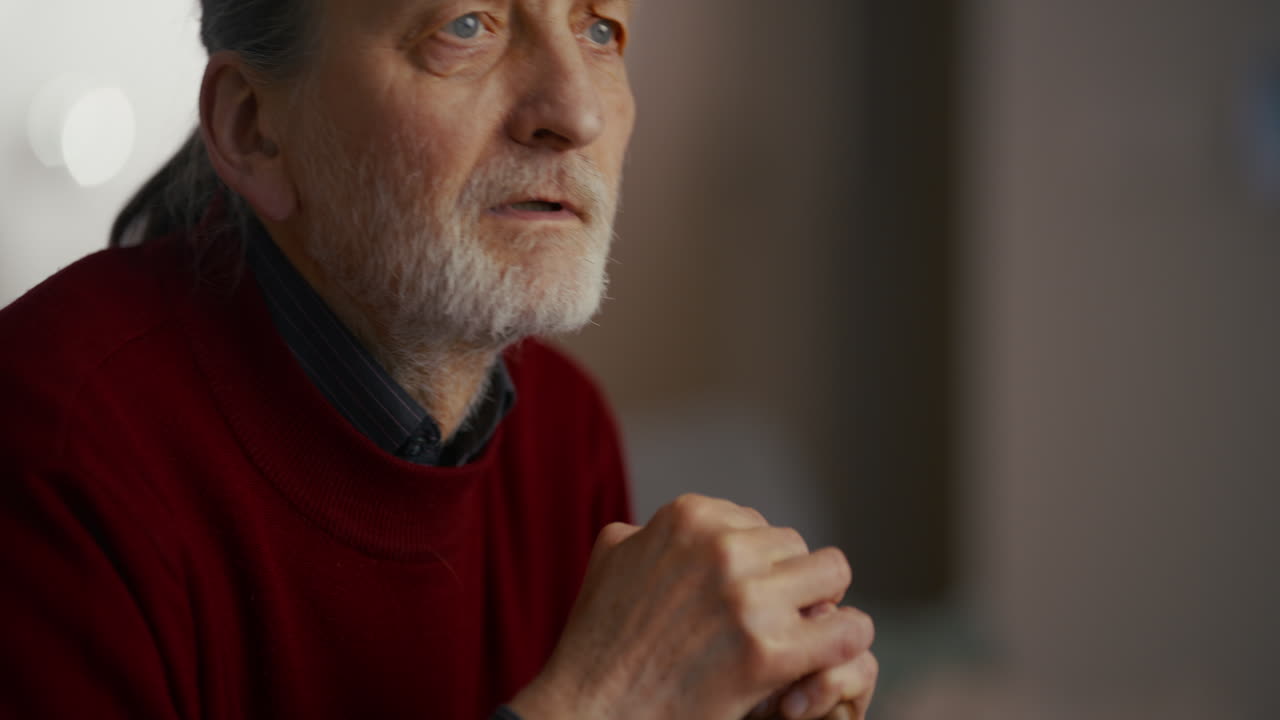 Close-up of Pensive Elderly Man with White Beard Holding a Walking Stick