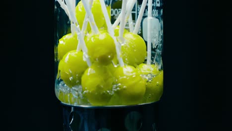 caramelos verdes de lollipop en los que se vierte agua sobre un tazón