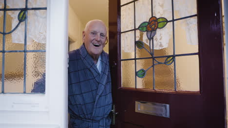 elderly man welcomes visitors at his front door