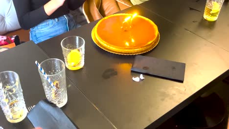 a group of friends celebrates an birthday, gathering around a cake and blowing out candles