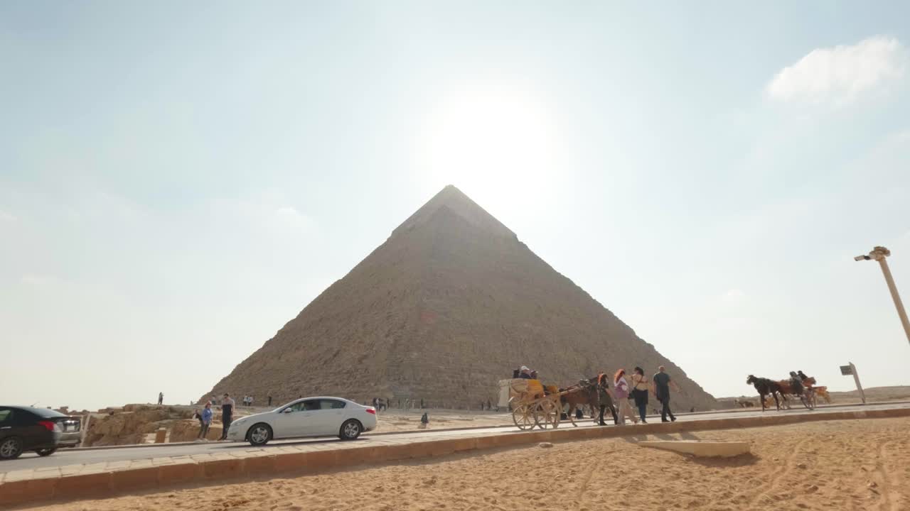 Turisti e carrozze trainate da cavalli vicino alla Grande Piramide di Giza in Egitto