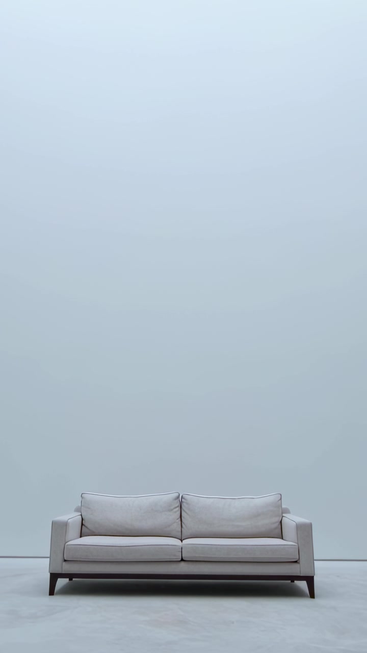 Vertikal video: Kameraet panorerer fra start og afslører en centreret sofa for at vise en høj væg i et showroom.