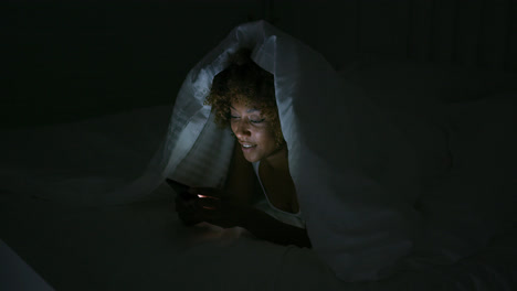 Young-woman-using-teléfono-in-dark-room