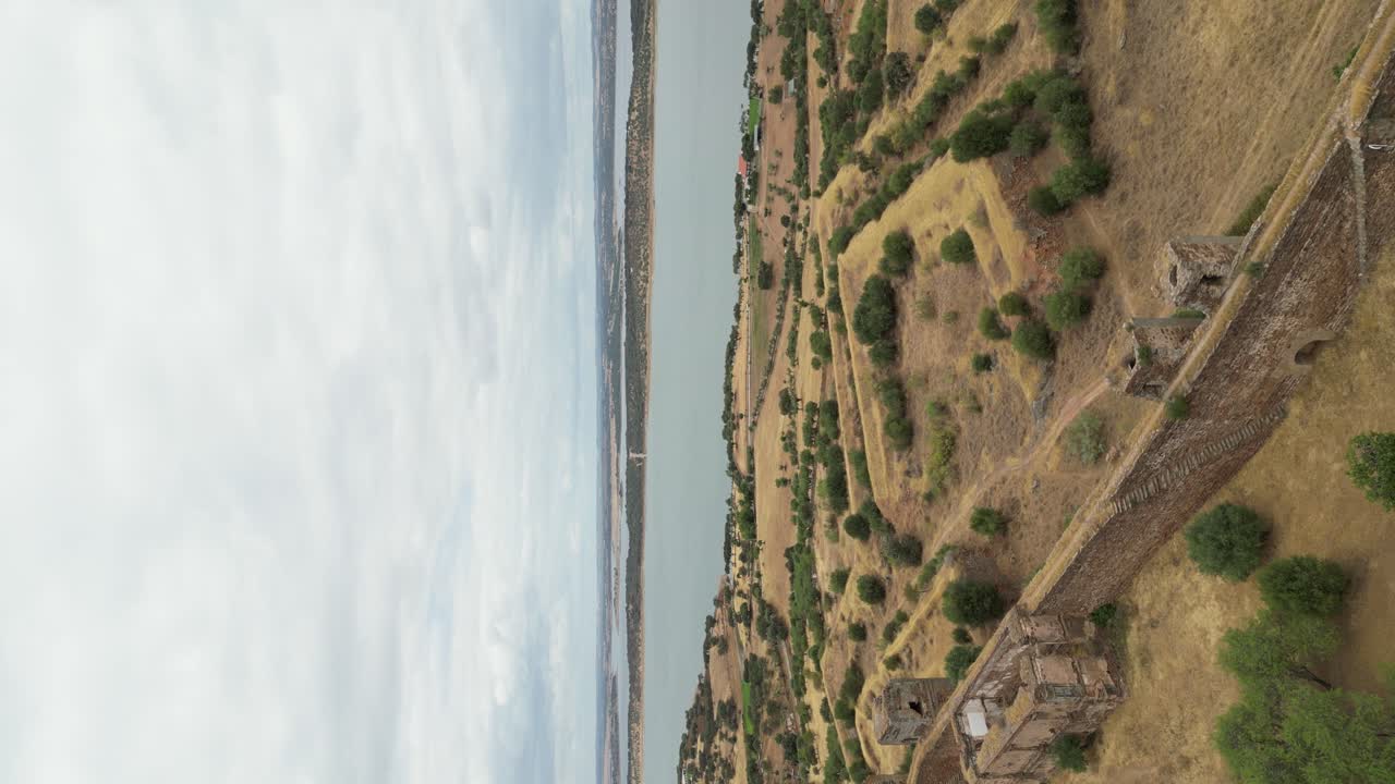 вертикальное видео, съемка с воздуха из замка муран с живописным озером алкуэва на заднем плане, сельская местность алентежу