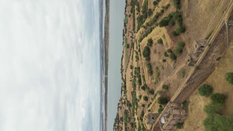 video vertical, retroceso aéreo del castillo de mourão con el pintoresco lago alqueva en el fondo, campo alentejano