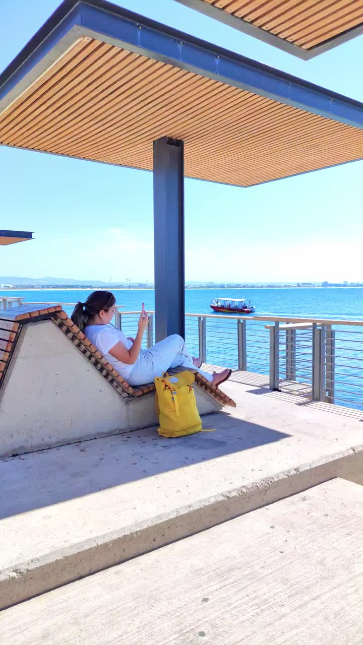 Woman relaxing on modern bench by akko sea